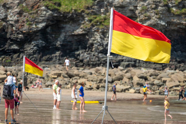 beach warning flag standing on the sands of st.agnes beach cove. - lifeguard association imagens e fotografias de stock