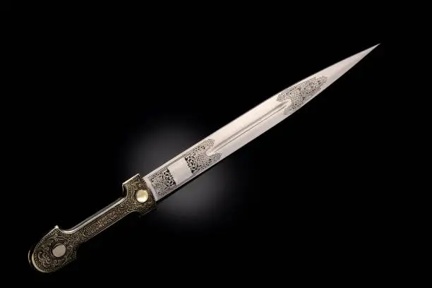 souvenir collectible silver dagger with scabbard on black. Luxury weapons with traditional Celtic patterns in a medieval vintage style.