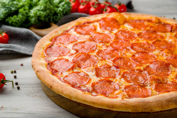 istock Pepperoni pizza on old grey wooden table macro close up 1369628726