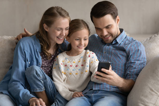 istock Happy small kid girl using cellphone with parents. 1369630152
