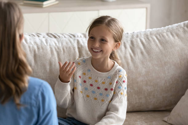 istock Smiling cute little girl practicing articulation with professional therapist. 1369630242