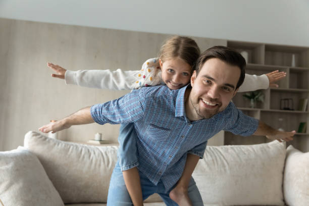 istock Happy caring young father holding on back joyful daughter. 1369630262