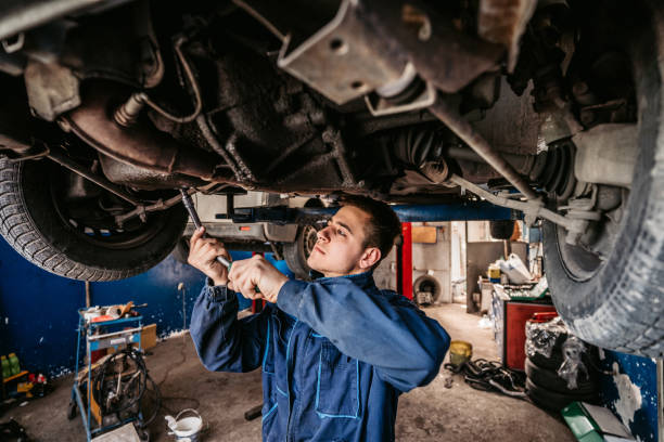 automechaniker repariert das auto in einer werkstatt - maintenance engineer car lamp protective workwear stock-fotos und bilder