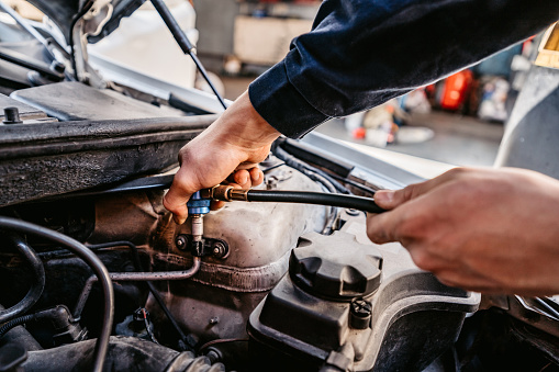 A close-up of auto mechanic fixing a car in mechanics garage. Repair service.