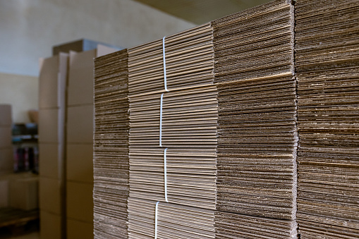 Folding cardboard boxes. Perforated sheets of corrugated cardboard are stacked on pallets. Packaging of finished products in industrial production.