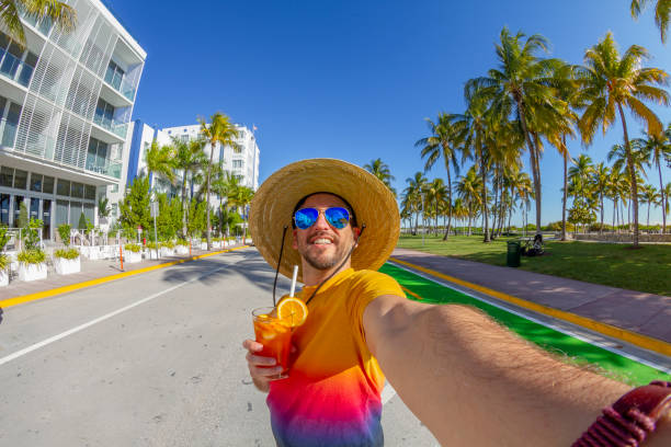POV Point of view selfie shot of a young travel male enjoying his vacations while drinking a cocktail in front of Ocean Drive, South Beach, Miami Beach, Miami, South Florida, United States of America POV Point of view selfie shot of a young travel male enjoying his vacations while drinking a cocktail in front of Ocean Drive, South Beach, Miami Beach, Miami, South Florida, United States of America in a sunny summer day.
The picture was taken at the famous and touristic Art Deco District. Shooting from a personal perspective in an exotic tropical beach travel holidays.
Travel Concept. 1 hotel south beach stock pictures, royalty-free photos & images