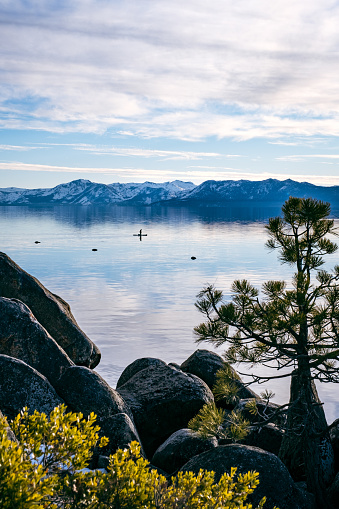 A person in the distance paddleboarding on Lake Tahoe in January.