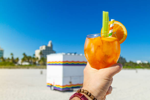POV Point of view shot of a young gay travel male enjoying his vacations while drinking a cocktail in front of Atlantic Ocean near to Ocean Drive at the most famous gay beach in South Beach, Miami Beach, Miami, South Florida, United States of America POV Point of view shot of a young gay travel male enjoying his vacations while drinking a cocktail in front of Atlantic Ocean near to Ocean Drive at the most famous gay beach in South Beach, Miami Beach, Miami, South Florida, United States of America.
The picture is in the famous and touristic Art Deco District. Shooting from a personal perspective in an exotic tropical beach travel holidays.
12th Street Beach is the most famous gay beach in Miami and part of the main strip of the famous South Beach. You'll find it where 12th Street and Ocean Drive converge.
Travel Concept. 1 hotel south beach stock pictures, royalty-free photos & images