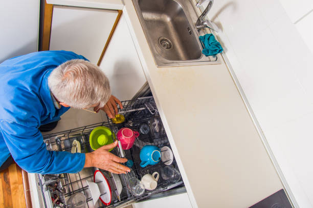 istock Senior serviceman fixing the dishwasher machine in kitchen 1369641351