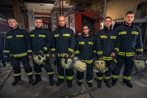 Portrait of firefighters standing by a fire engine.