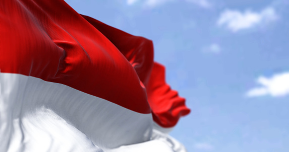 Detail of the national flag of Indonesia waving in the wind on a clear day. Democracy and politics. Patriotism. Selective focus. South east Asian country.