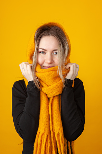 Close-up studio portrait of a 23 year old woman in a yellow scarf on a yellow background
