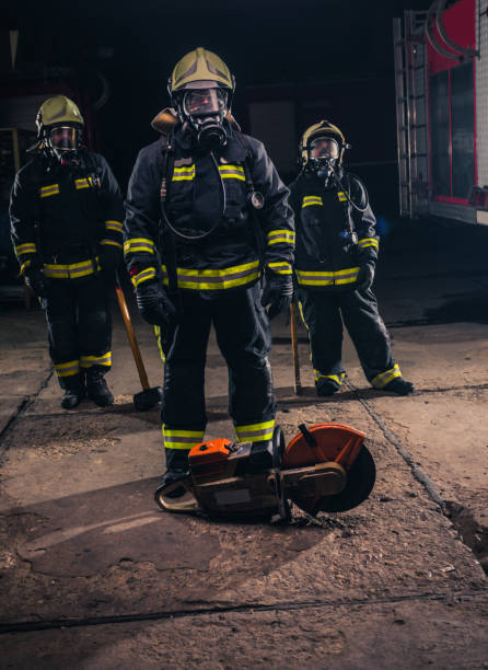 istock Group of three young fireman posing inside the fire department with uniform and tools 1369643979