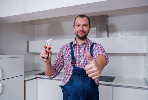 istock Young serviceman in uniform with a pliers standing in the kitchen 1369645305