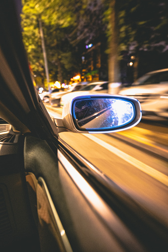 The rear mirror of a fast-moving car at night