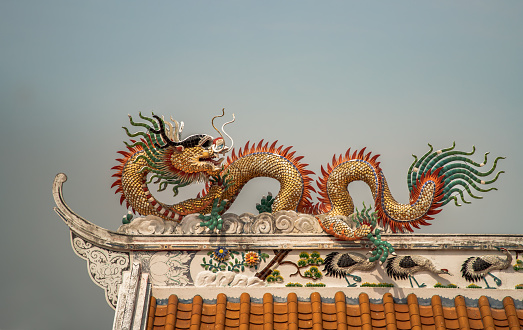 Chinese dragon sculpture decorate on chinese-style temple roof in blue sky background. Copy space, Selective focus.