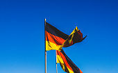 zwei-deutsche-flaggen-am-blauen-himmel.j