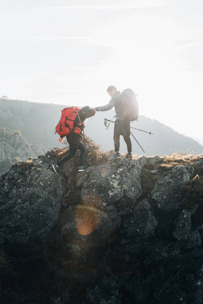 backpacker bieten helfende hand auf einem berggipfel - tranquil scene joy vacations high angle view stock-fotos und bilder