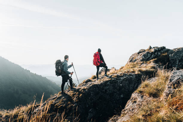 young couple backpack up a mountain summit - wandelen stockfoto's en -beelden