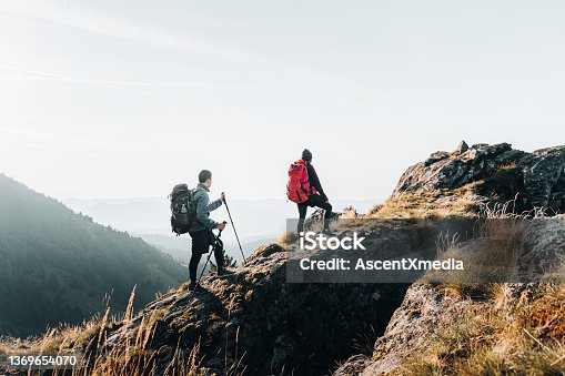 istock Young couple backpack up a mountain summit 1369654070