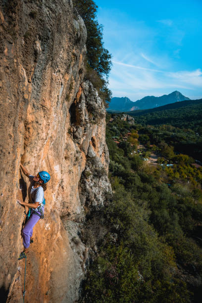 istock Climber ascends steep rock wall above lush valley 1369655144