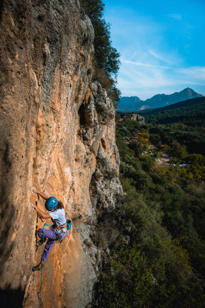 istock Climber ascends steep rock wall above lush valley 1369655207