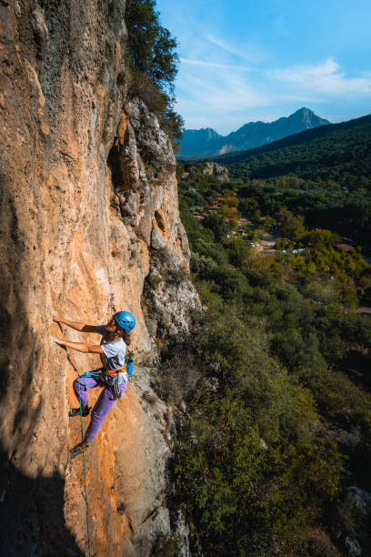 istock Climber ascends steep rock wall above lush valley 1369655222