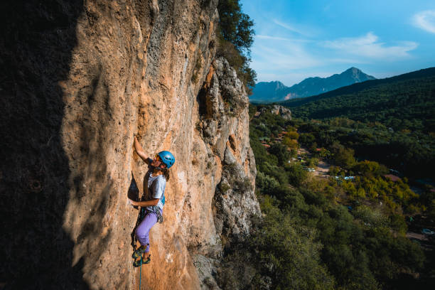istock Climber ascends steep rock wall above lush valley 1369655264