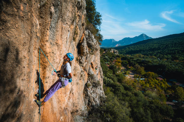 istock Climber ascends steep rock wall above lush valley 1369655407