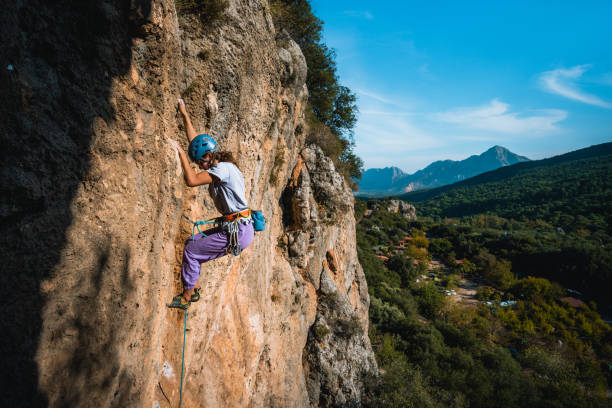istock Climber ascends steep rock wall above lush valley 1369655445