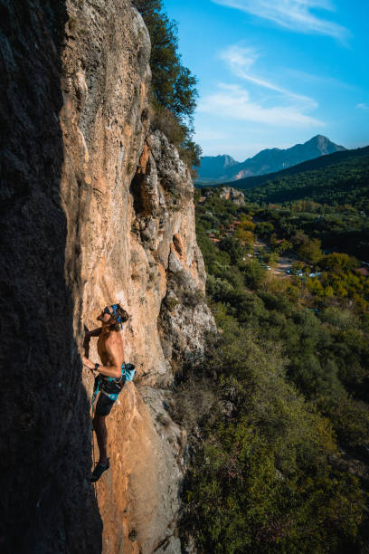 istock Climber ascends steep rock wall above lush valley 1369655523