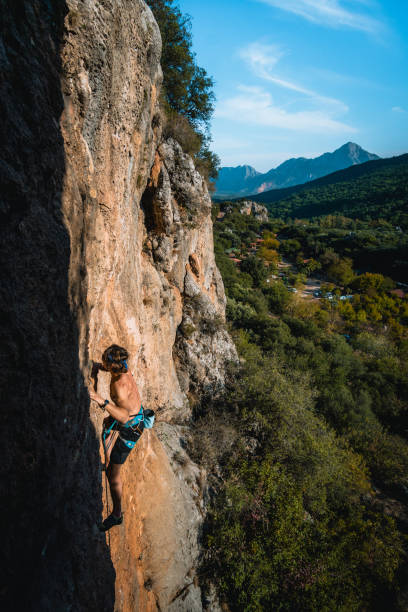 istock Climber ascends steep rock wall above lush valley 1369655527