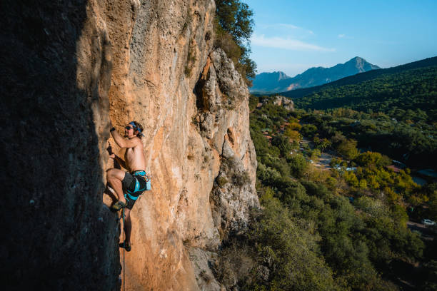 istock Climber ascends steep rock wall above lush valley 1369656133