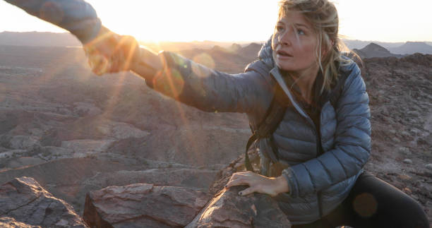 jovem se aproxima para ajudar a mão acima das montanhas - human hand light reaching assistance - fotografias e filmes do acervo