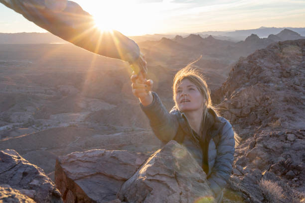 jovem se aproxima para ajudar a mão acima das montanhas - human hand light reaching assistance - fotografias e filmes do acervo