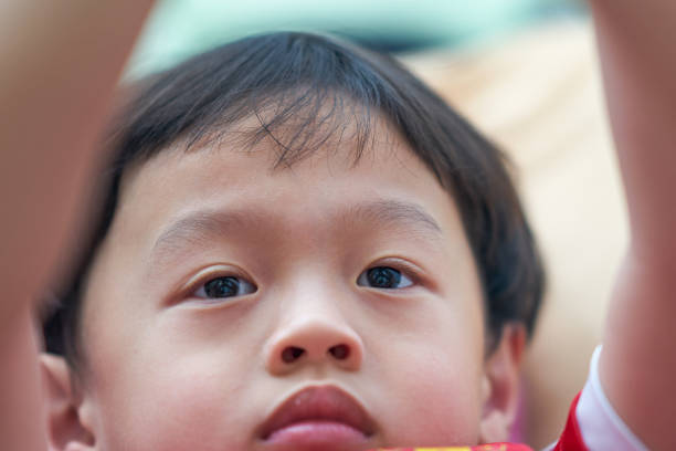 A little boy eats a chocolate ice cream candy on a stick. Close-up of a child's face. Palm trees in the background. Concept: summer mood, holidays, travel, vacation
