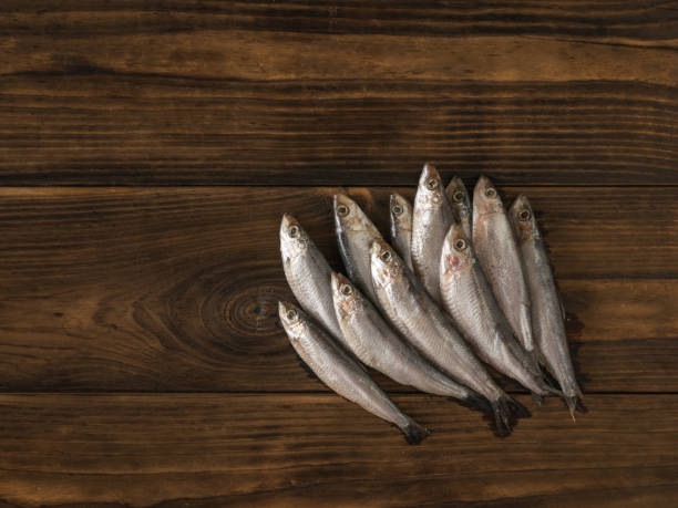 istock Salted sprat fish on a dark wooden table. 1369666324
