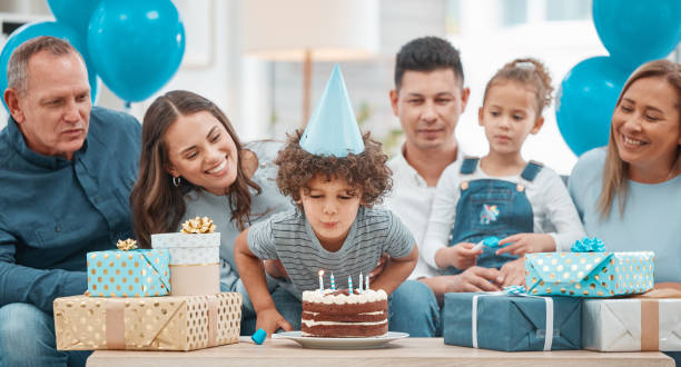 shot of an adorable little boy celebrating a birthday with his family at home - little cakes imagens e fotografias de stock