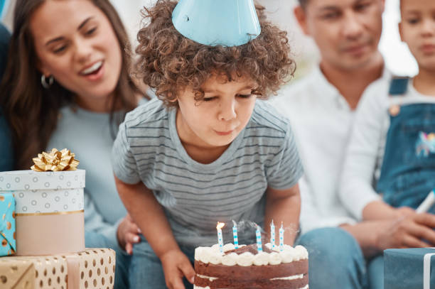 aufnahme eines entzückenden kleinen jungen, der mit seiner familie zu hause einen geburtstag feiert - six candles stock-fotos und bilder