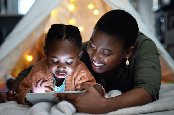 집에서 취침 중에 그녀의 어머니와 함께 디지털 태블릿을 사용하여 사랑스러운 어린 소녀의 샷 - ipad 2 뉴스 사진 이미지