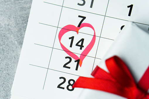 Close up calendar with 14 February date Valentines day with red heart shape marker and gift box with ribbon. Present for birthday or anniversary