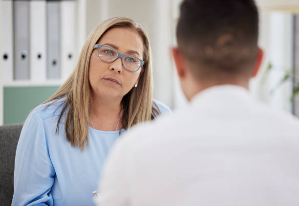 scatto di uno psichiatra maturo seduto con il suo paziente durante una consultazione nella sua clinica - patient doctor male talking foto e immagini stock