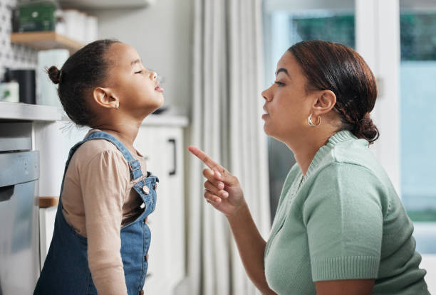 scatto di una bambina che viene parlata severamente a casa da sua madre - punishment foto e immagini stock