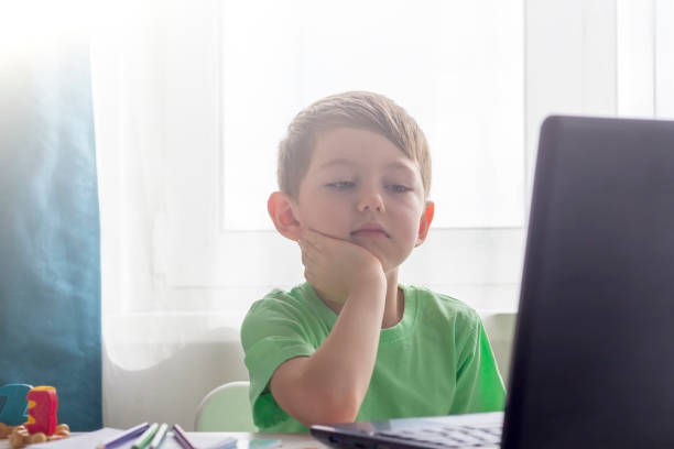 istock Distance learning, online education. Social distance and self-isolation during quarantine. Preschooler or schoolboy studying at home with notebook and doing homework for development school. 1369685125
