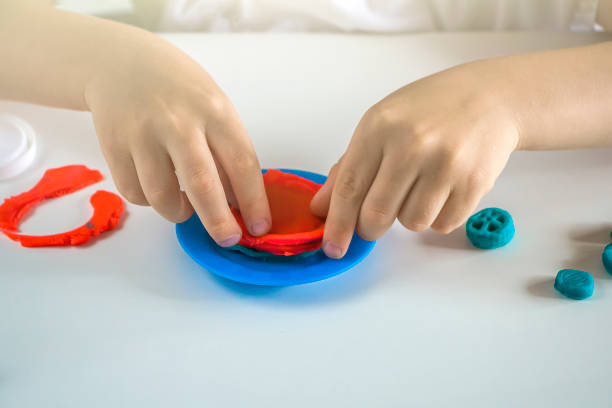 istock Kids creativity. Plasticine modeling for child development at home.  Boy creating toys from play dough close up. Blurry, selective focus on forms, backlight 1369686309