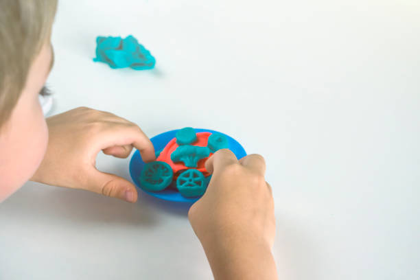 istock Kids creativity. Plasticine modeling for child development at home.  Boy creating toys from play dough close up. Blurry, selective focus on forms, backlight 1369686311