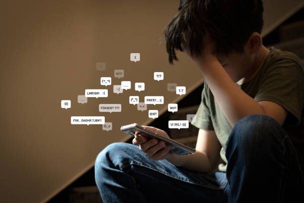 Asian preteen boy sitting at stair, covering his face with hands, face down, holding smartphone in low light. Asian teenage boy sitting at stair, covering his face with hands, face down, holding smartphone in low light feeling frustrated, lonely, stress and depressed. Cyber bullying concept. cyberbullying stock pictures, royalty-free photos & images
