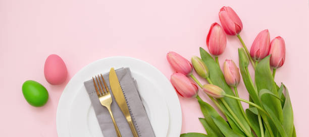 istock Easter table setting. Egg and tulip pastel color and gold cutlery on pink, overhead 1369689672