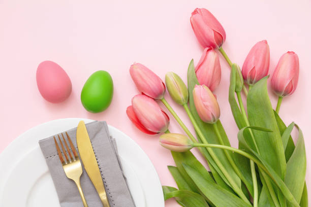 istock Easter table setting. Egg and tulip pastel color and gold cutlery on pink, overhead 1369689675