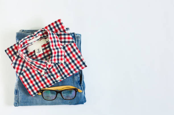 stack of plaid shirt and jean with glasses on white background, copy space